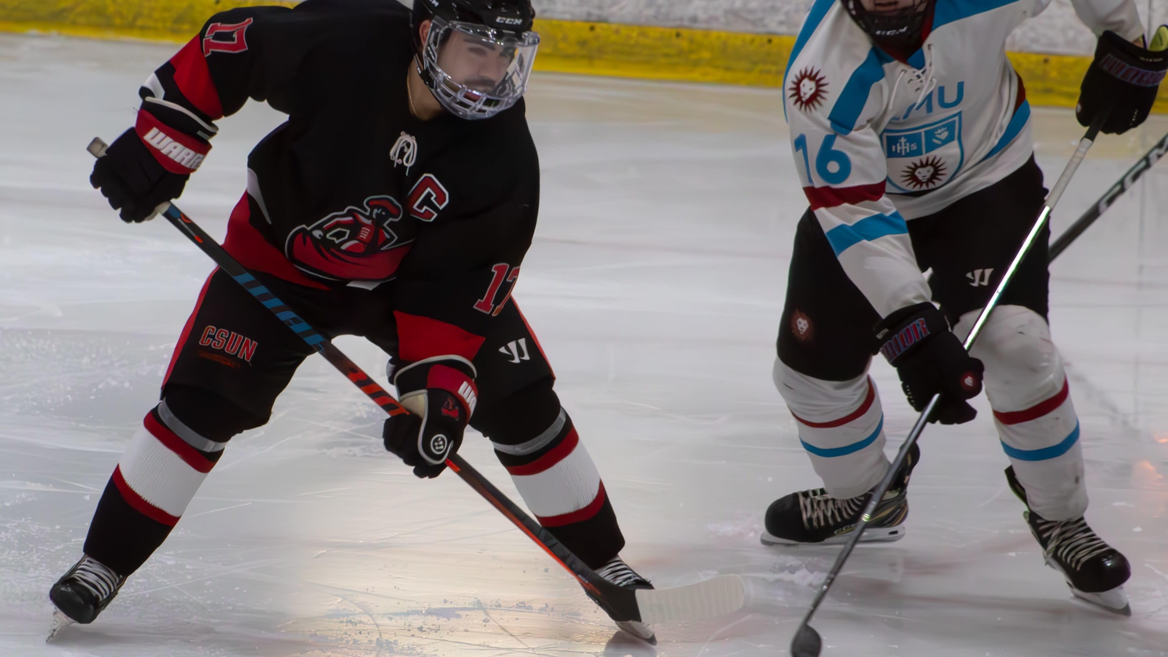 CSUN hockey players drives puck attempting to steal from opposing team player.