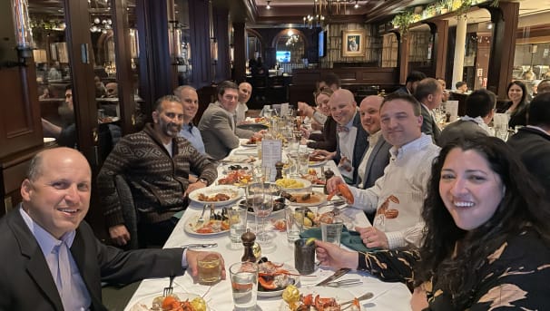Group of individuals sitting at a table at a restaurant eating dinner
