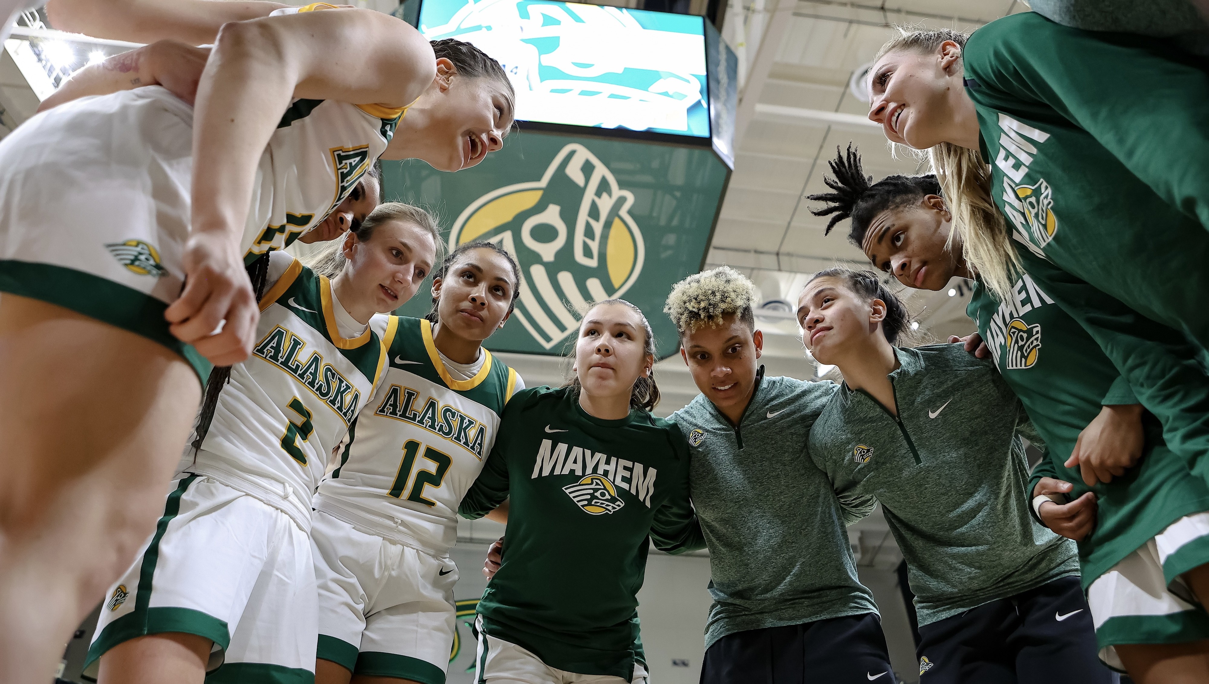 UAA Women's Basketball team huddling together at a game