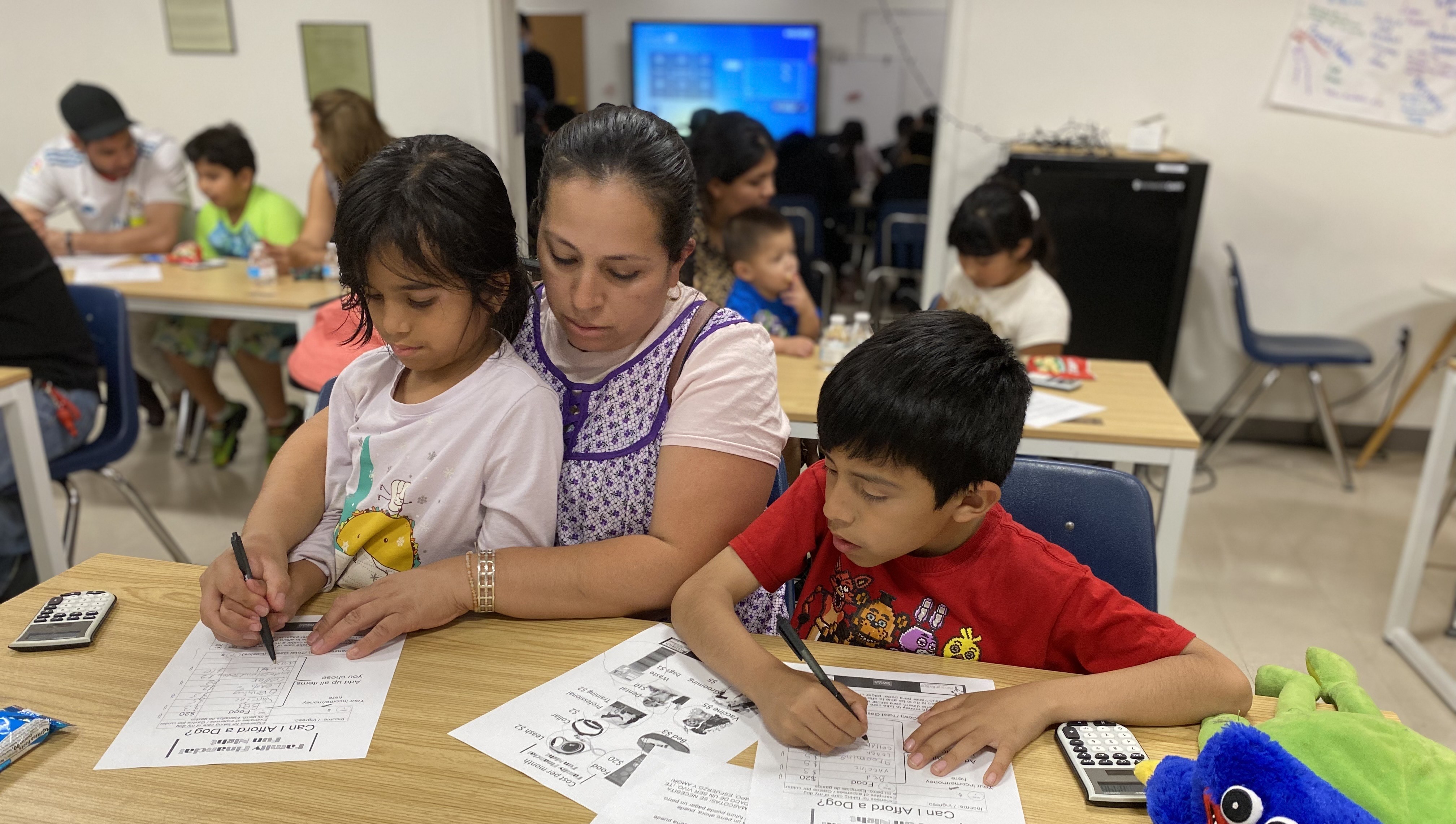 A family engaging in introductory financial literacy lessons during Family Financial Fun Night.