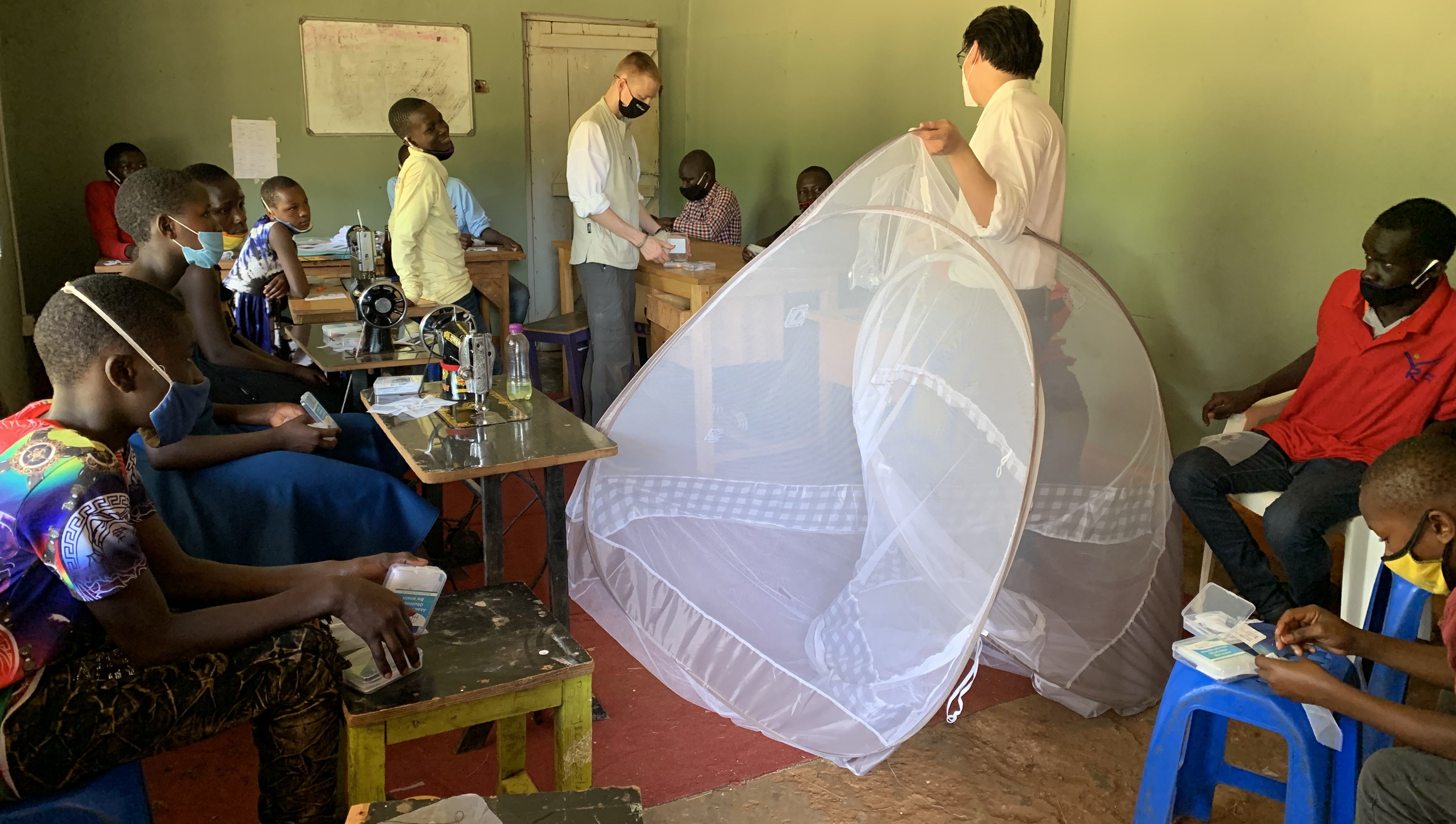 Ben and Michael teaching a group of students how to use their mosquito net repair kits.