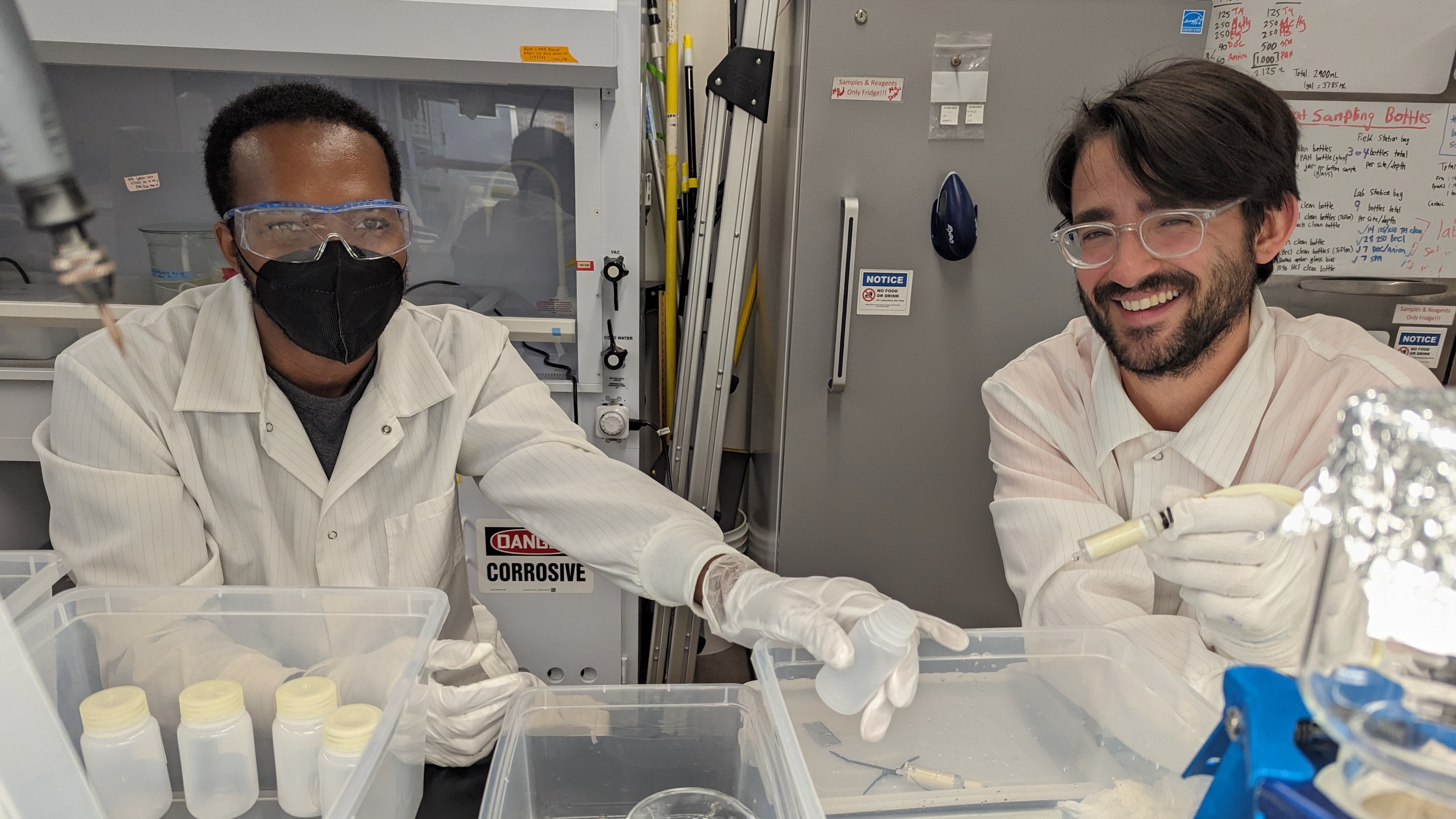 Three researchers in rain gear take river measurements with a probe and cables along the bank.