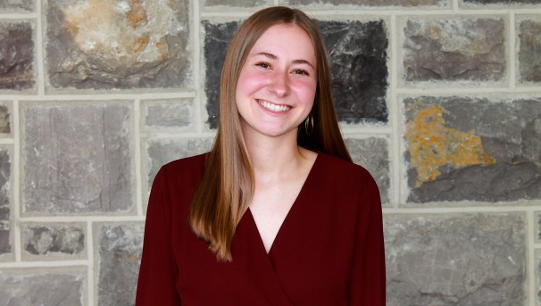 Julia stands smiling in front of a wall of Hokie Stone