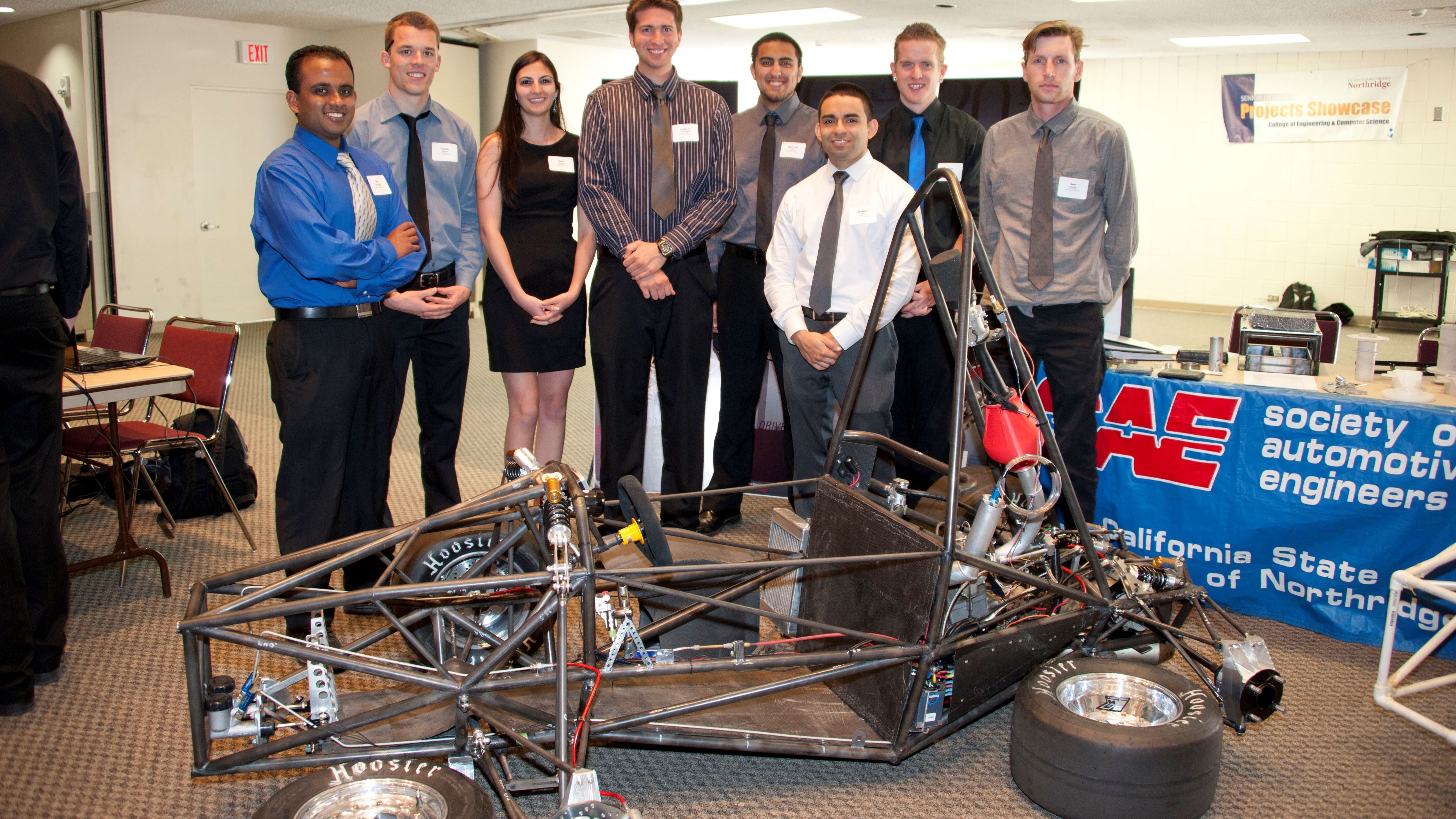 CSUN engineering students stand beside their Formula SAE race car at the senior project showcase.