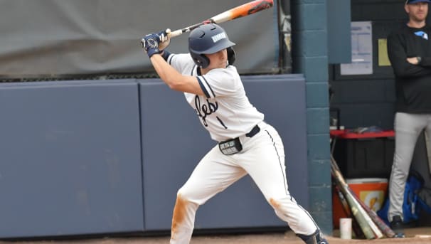 A baseball student-athlete is up to bat and is taking a stance, ready to swing.