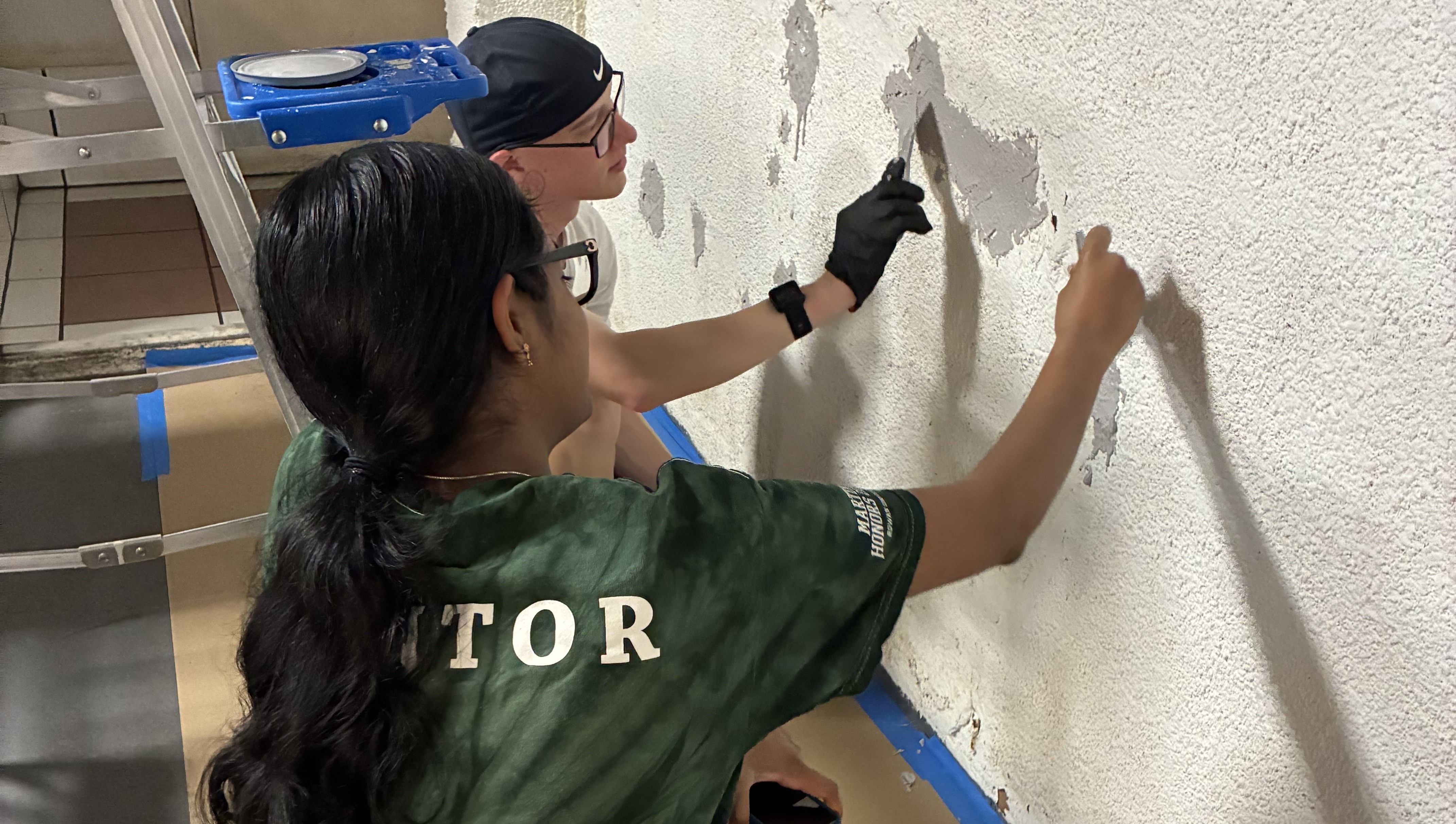 EWB students pathcing walls to restore building.
