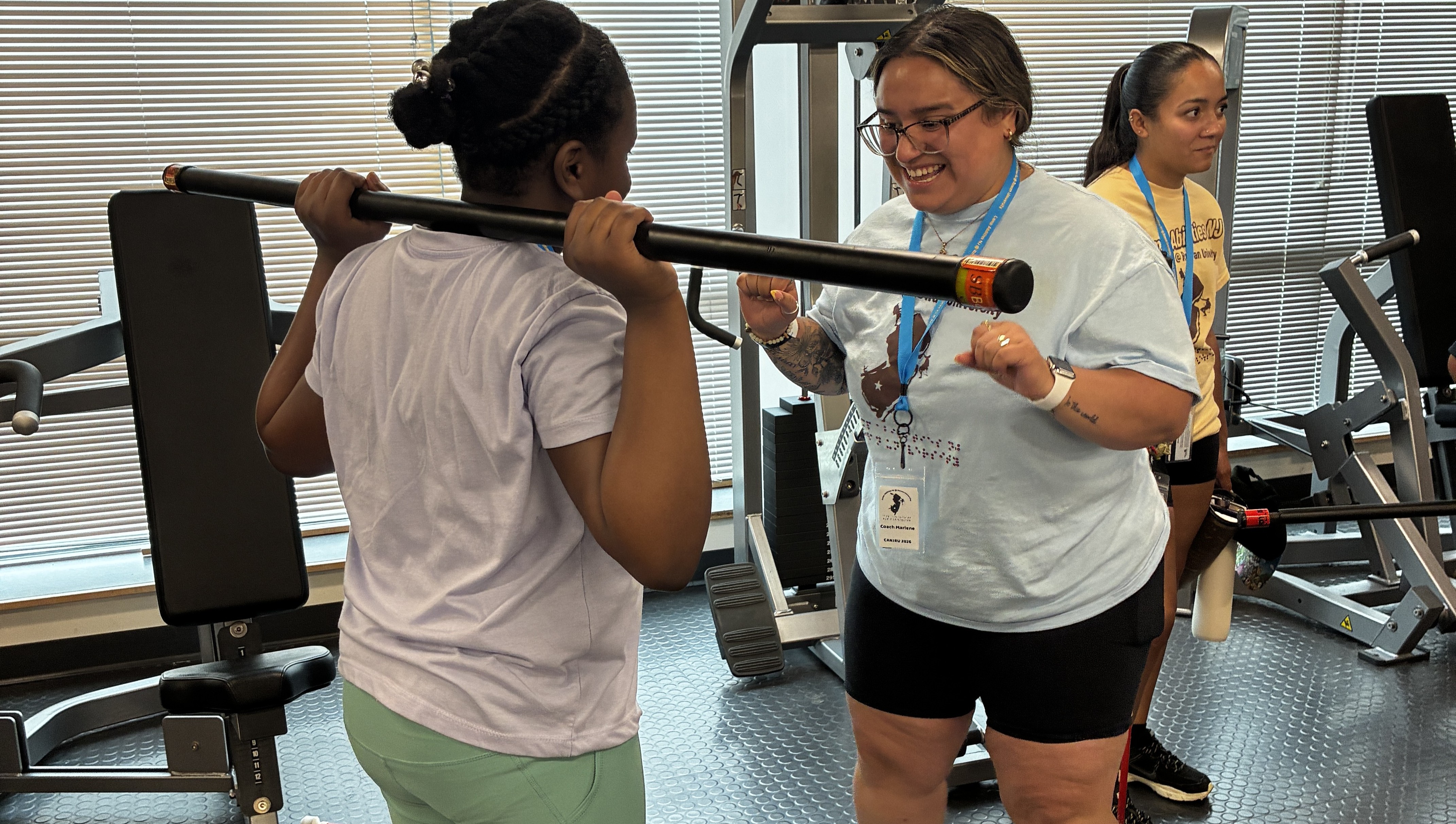 Camper and trainer lifting weights in the gym.