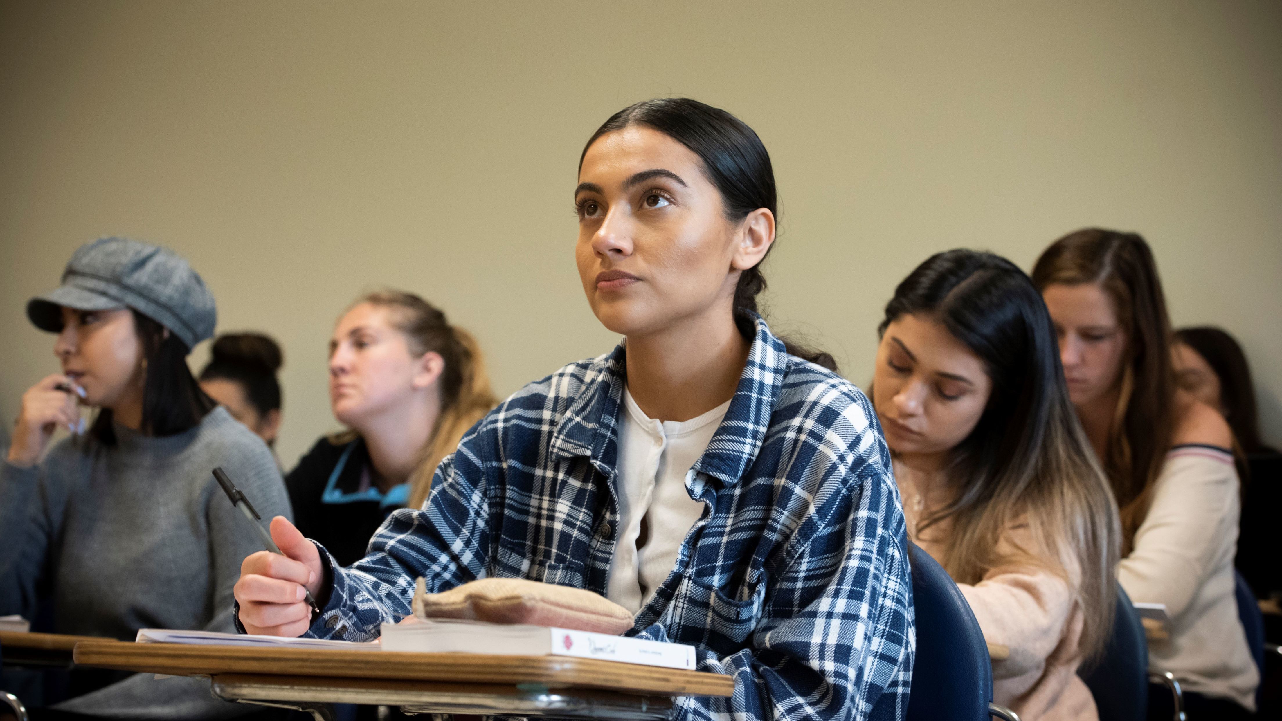 CSUN students attentively listening and taking notes during a classroom lecture.