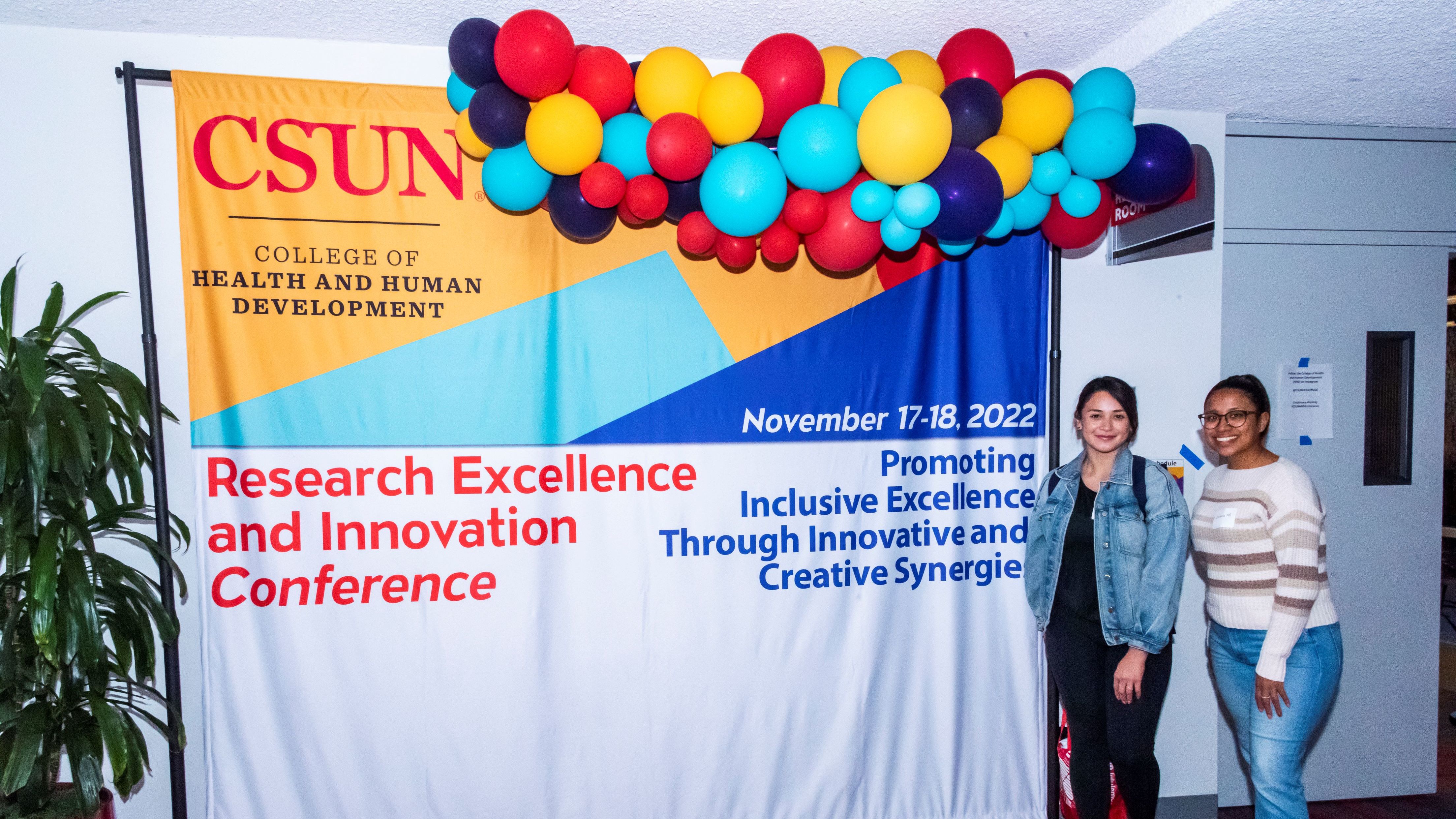 Students stand beside a CSUN College of Health and Human Development conference banner.