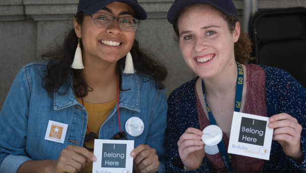 Two smiling Berkeley Connect students show off their stickers that read "I belong here"