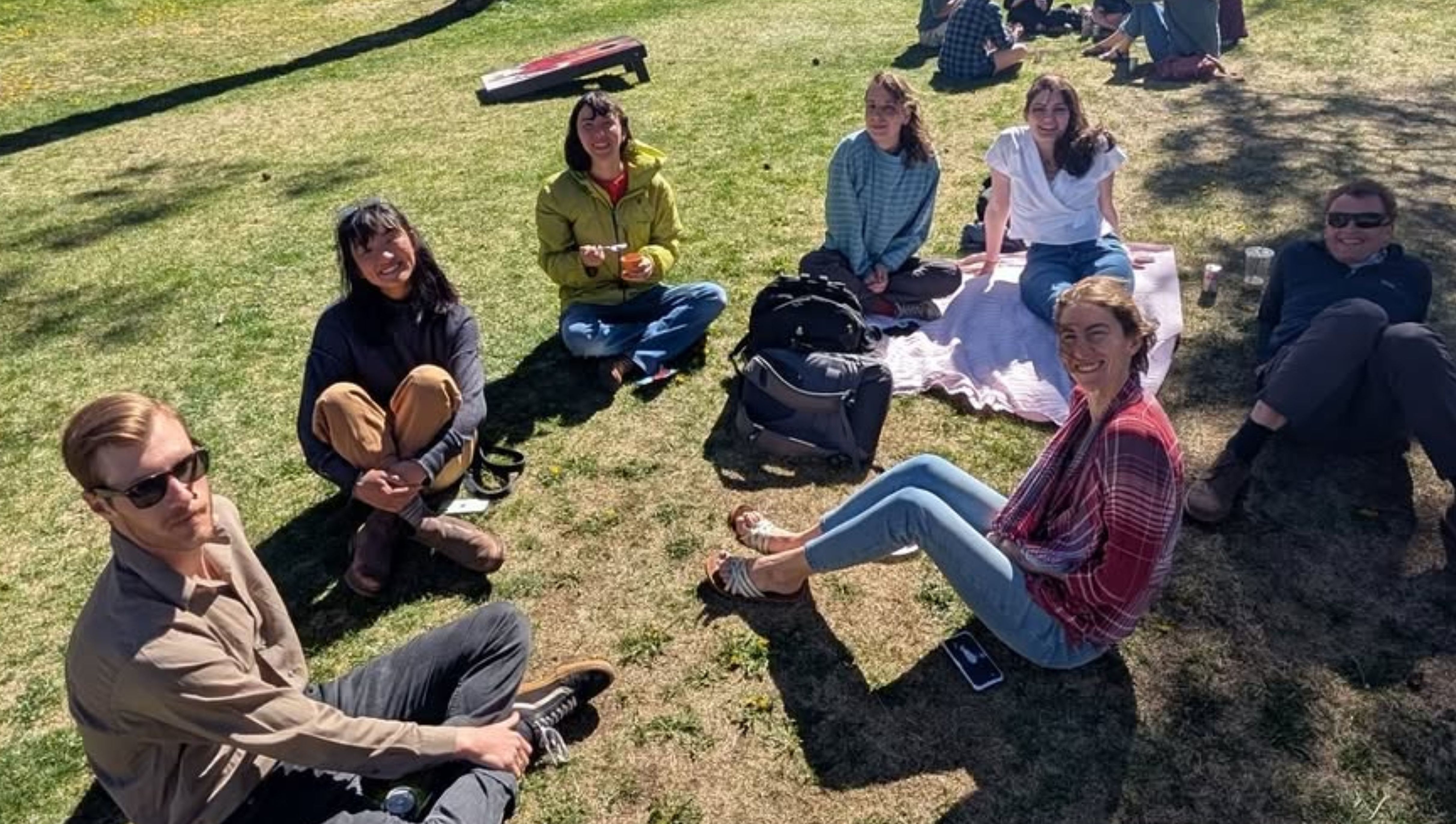 An image of a group of smiling graduate students at the end of year picnic.