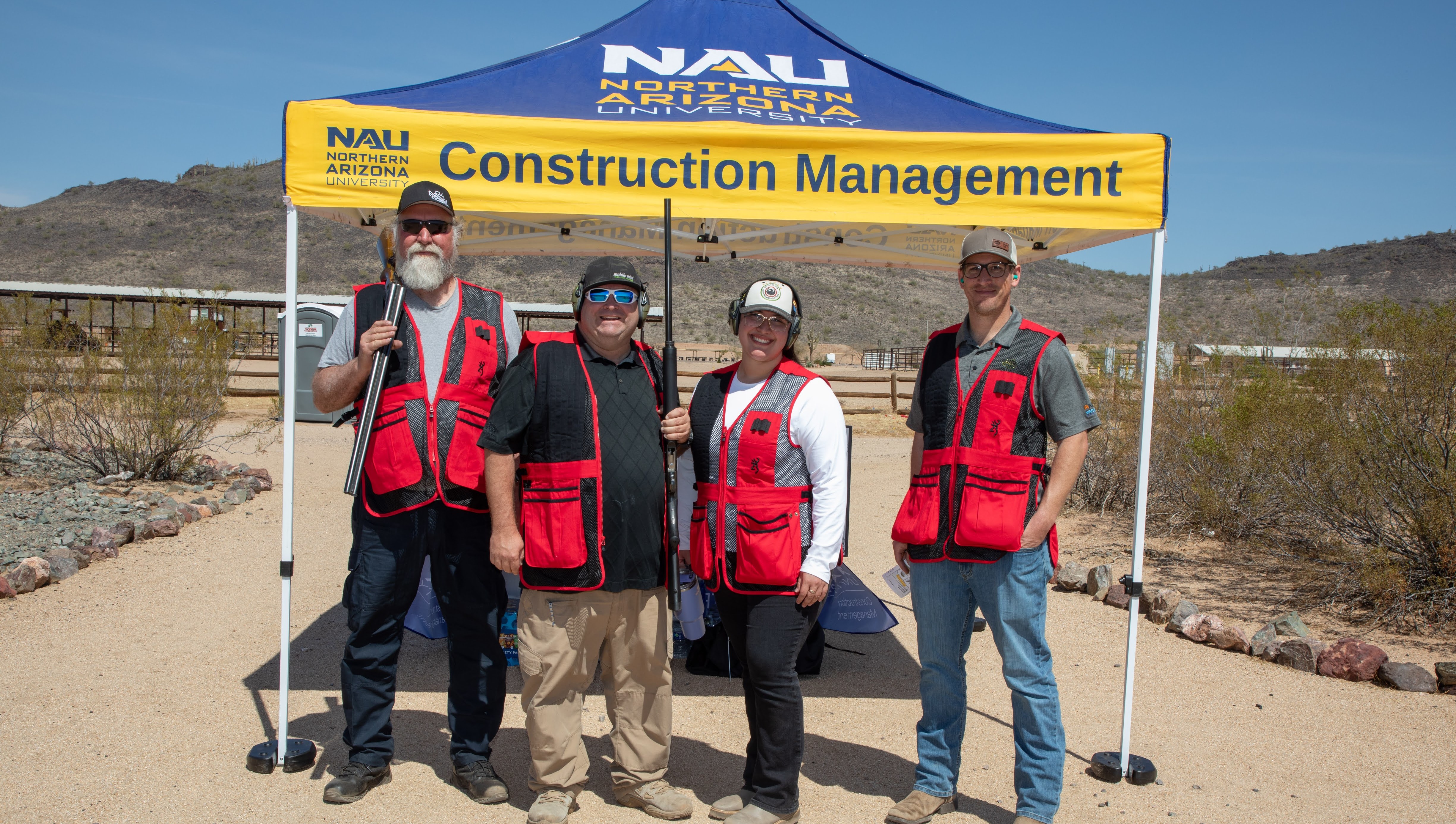 1 Foursome team in red vests posing by the NAU Construction Management tent