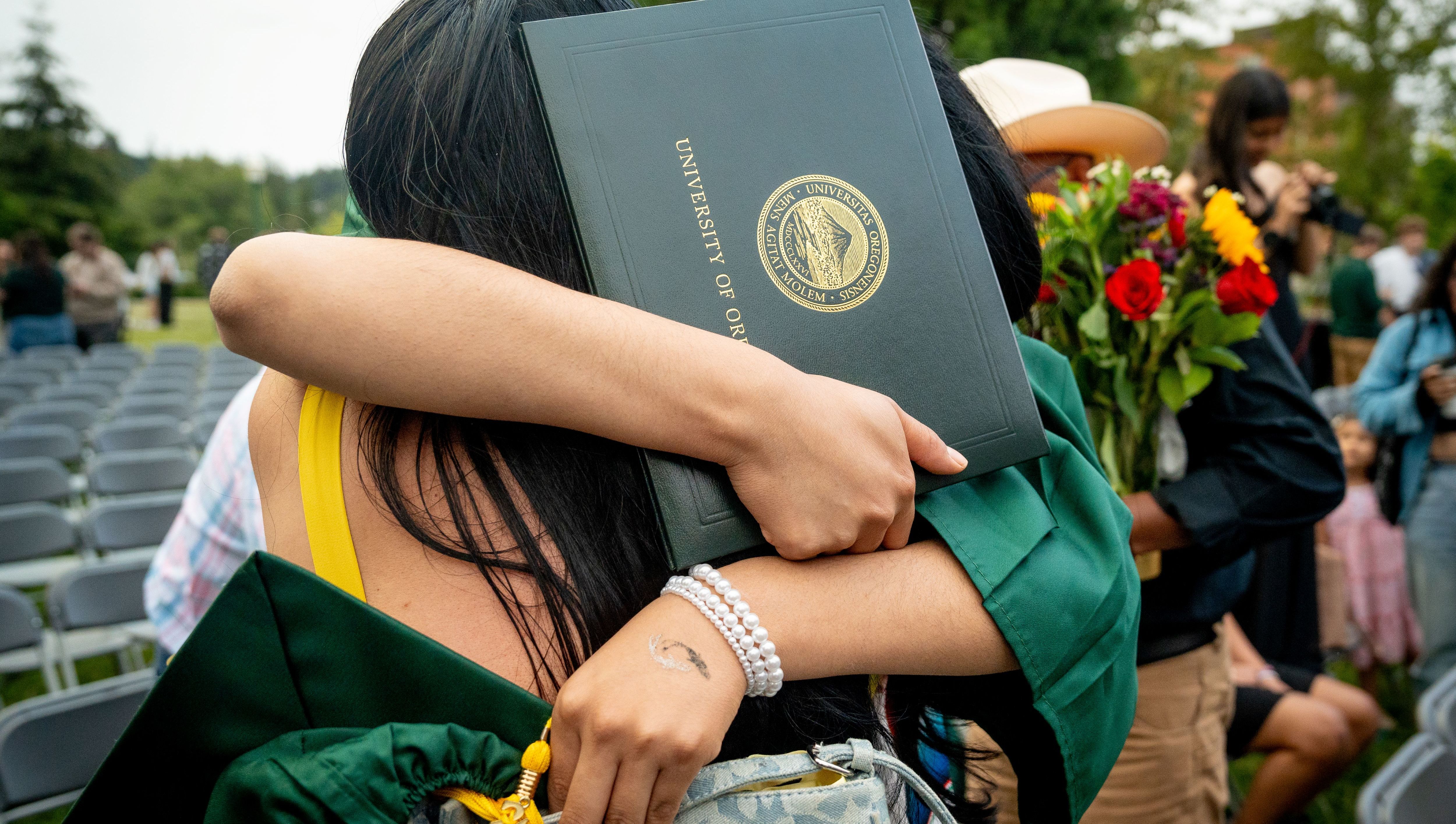 Students hug at the UO graduation.