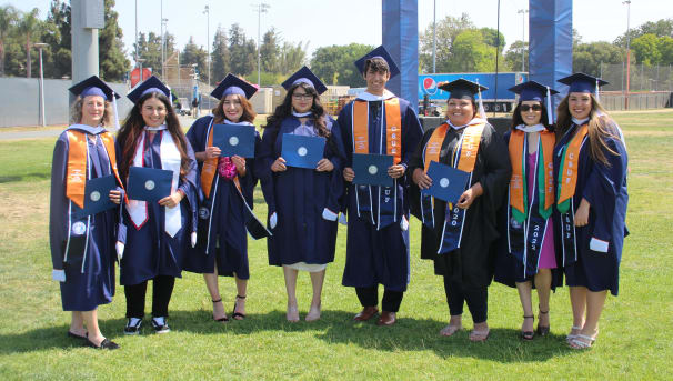 Psychology students in CSUF regalia holding diplomas