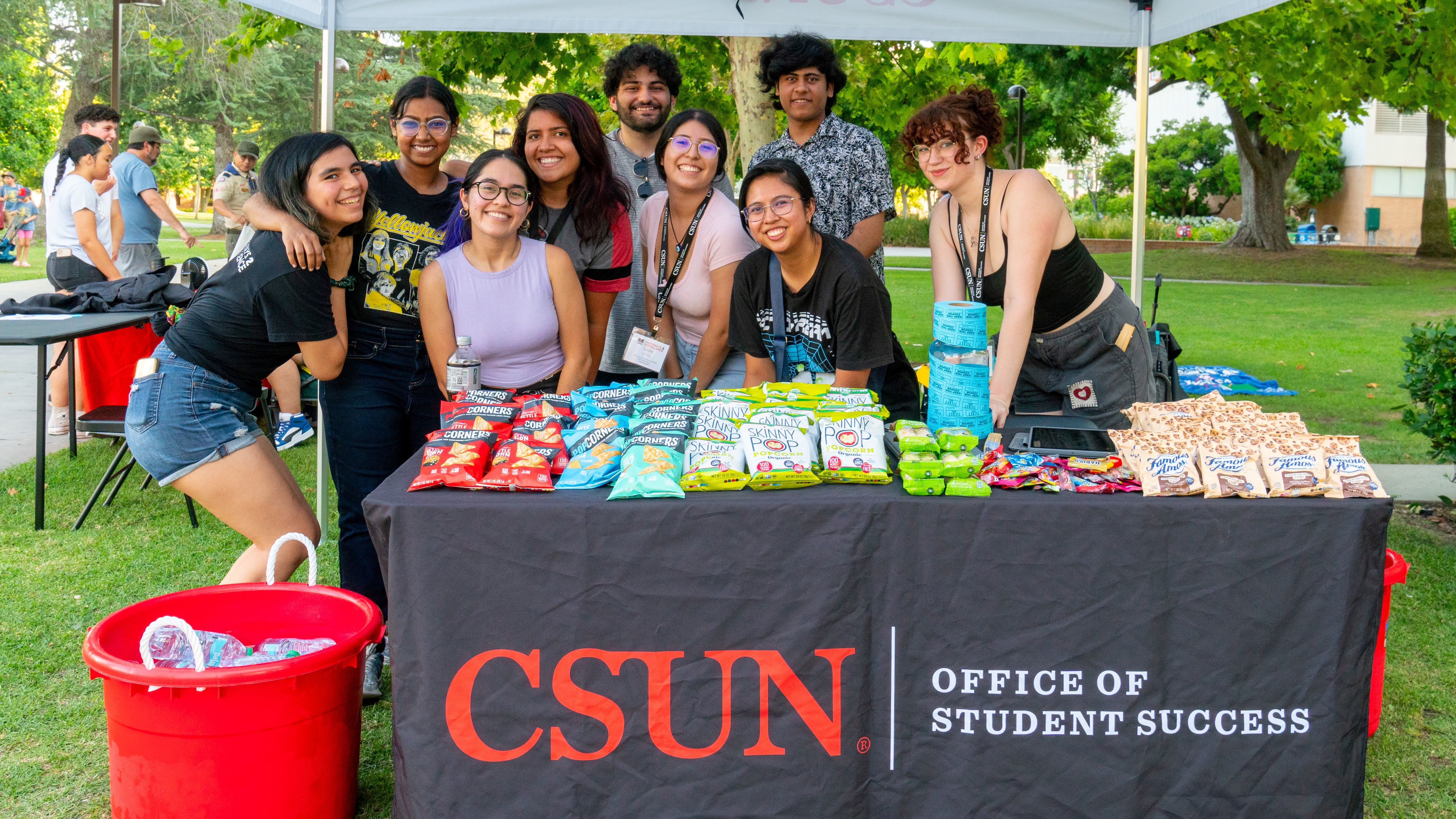 Group of students in front of table with snacks on it, and Office of Student Success wordmark
