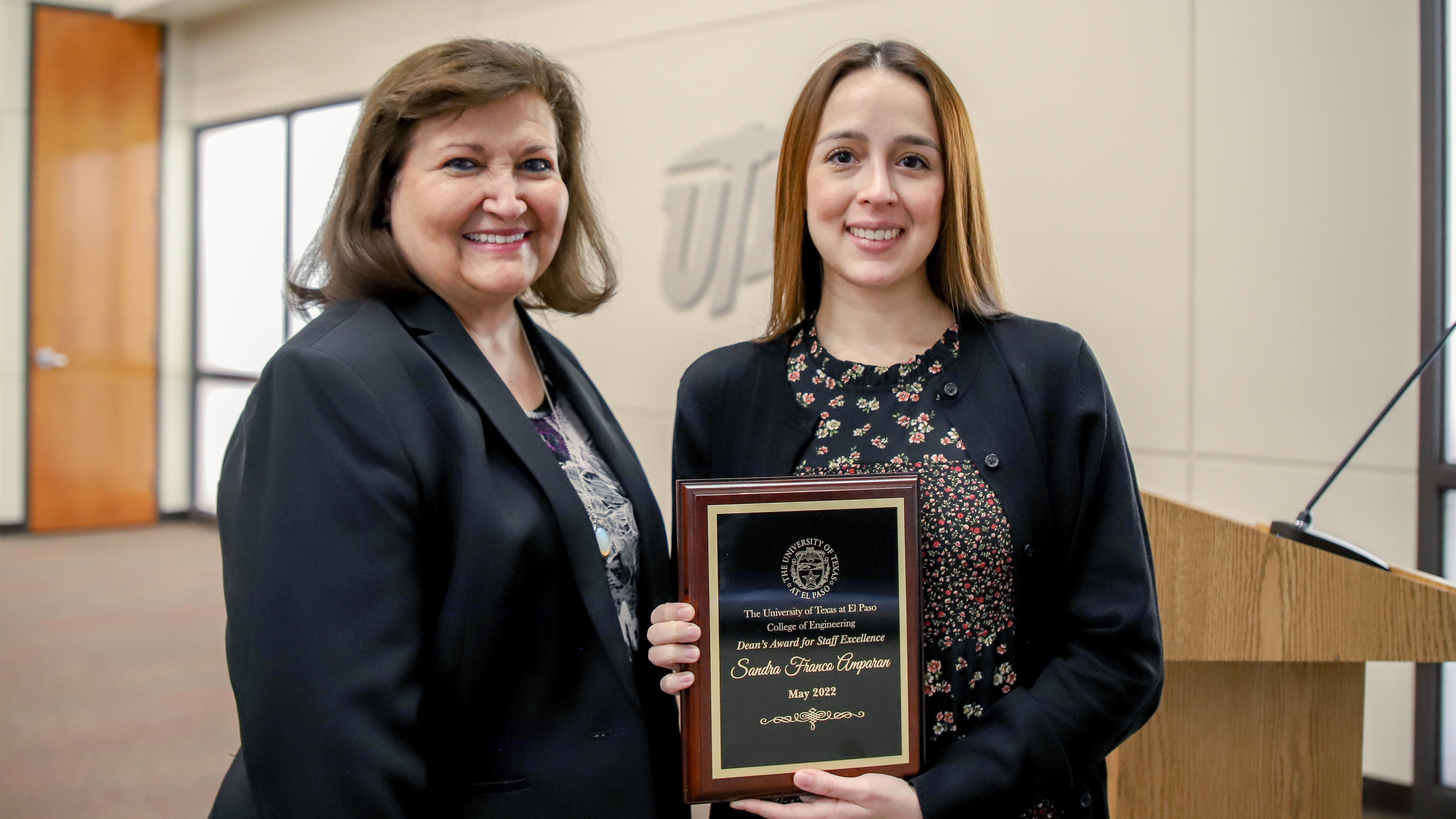 Two women posing with Dean's Award for Staff Excellence plaque