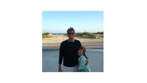Two individuals standing next to each other smiling with the beach in the background