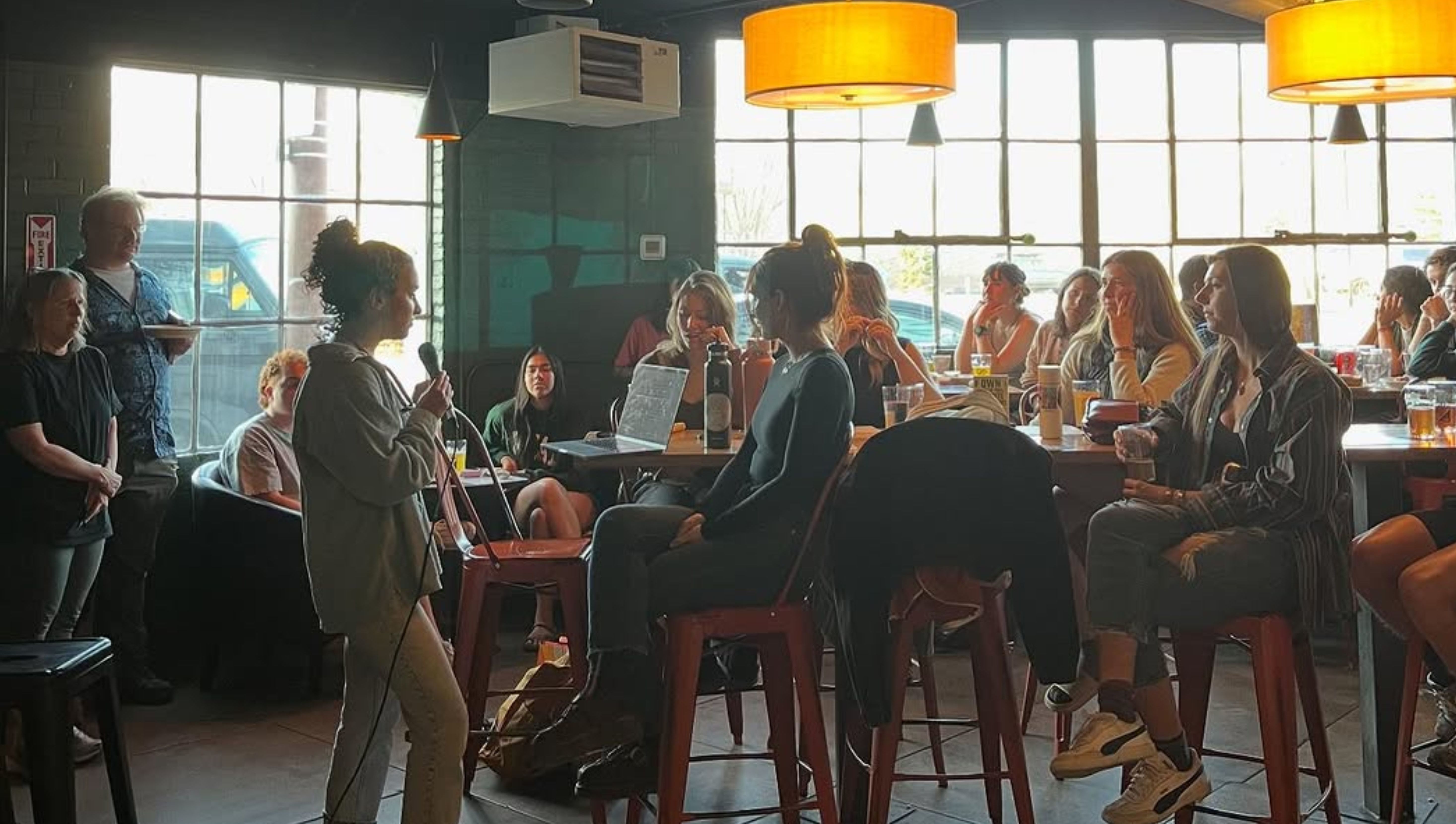 An image of a speaker at Science on Tap, talking to a group pf people at a table.