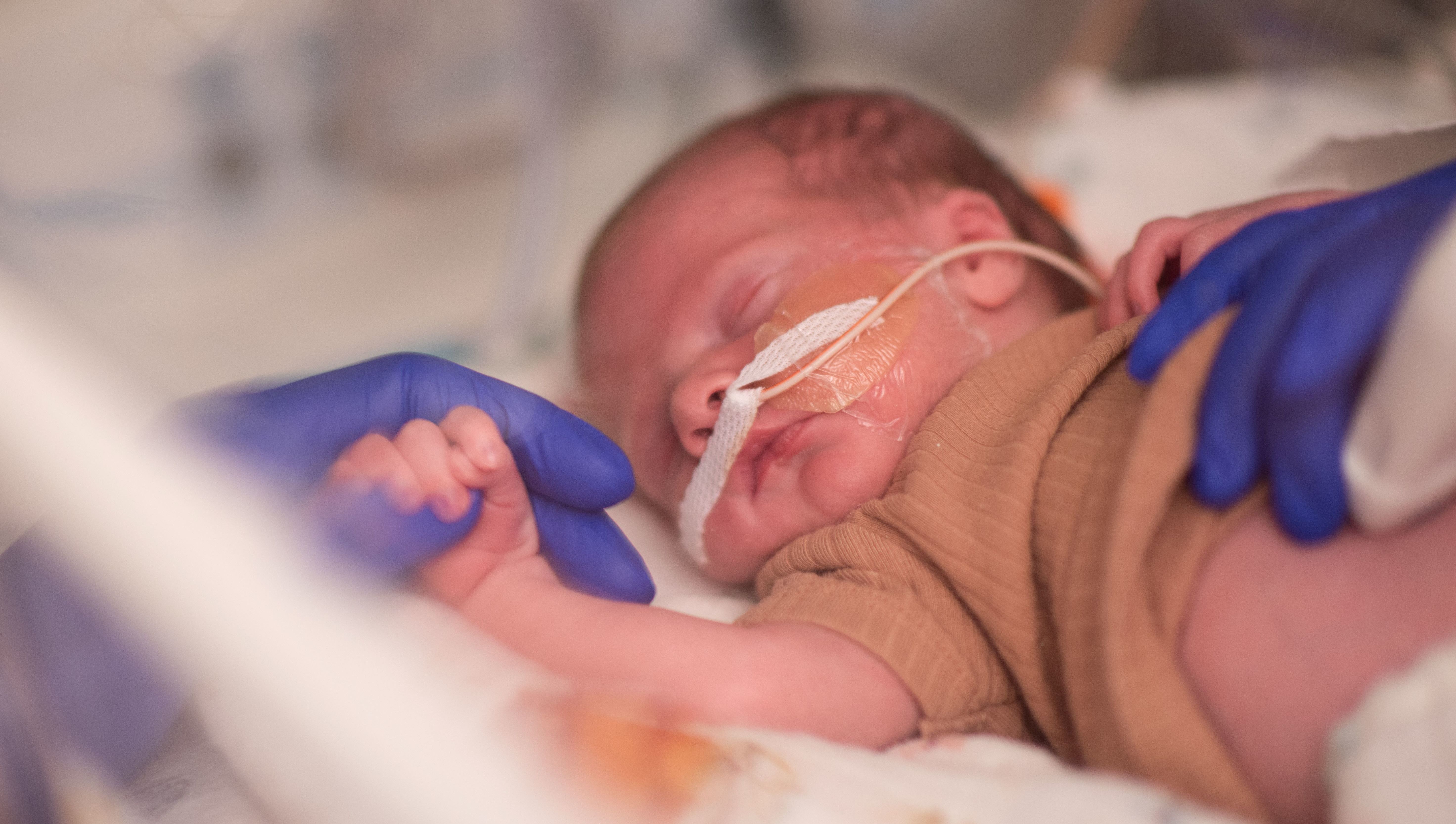 NICU baby holding nurses hand