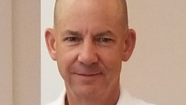 Clark Swanson smiling towards the camera, wearing a white coat