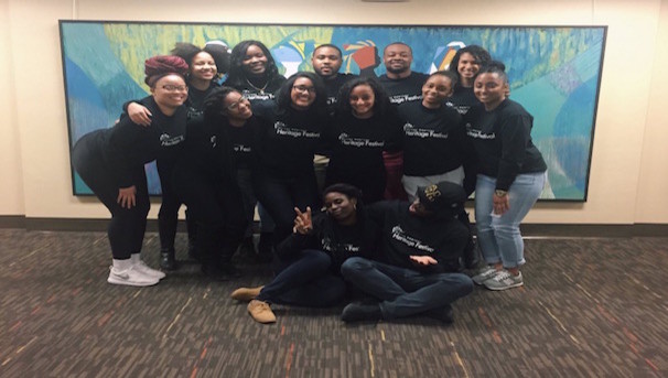 Students posed before a colorful painting at the Heritage Festival, 2017