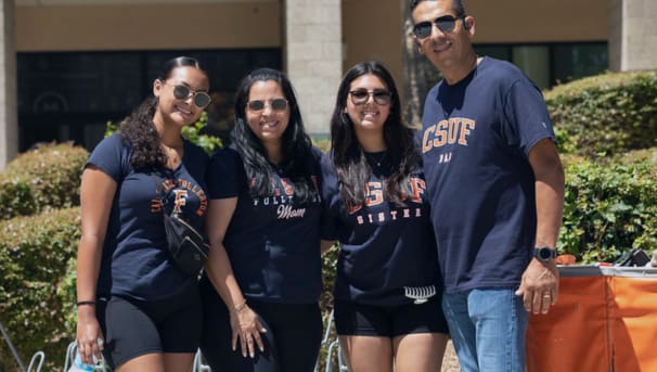 family members dressed in CSUF spirit gear smiling at the camera