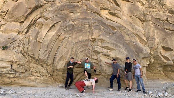 Students in the field in front of a giant rock