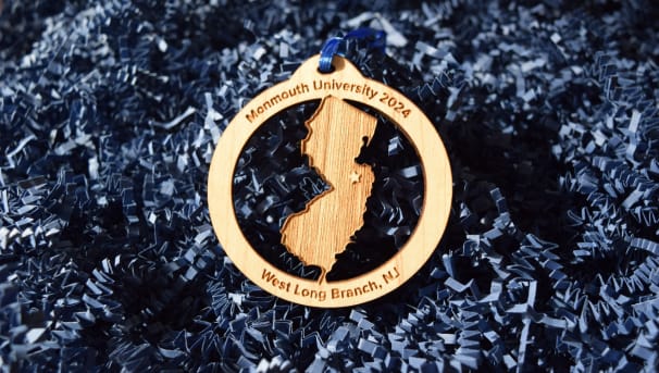 Wooden ornament with NJ cut out, star above West Long Branch on map. Monmouth University 2024 on top