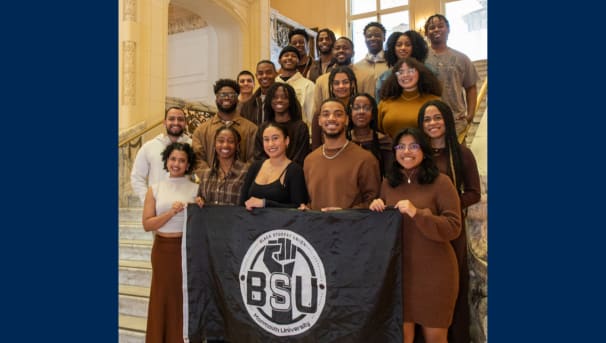 Group of BSU members on the Great Hall steps posing for a phot with BSU flag