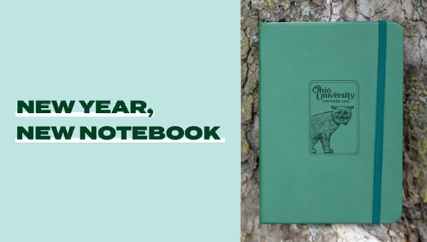 Journal January notebook in front of a tree with New Year New Notebook headline on the left