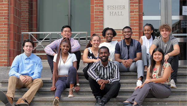 10 students sitting on the front steps of Fisher Hall