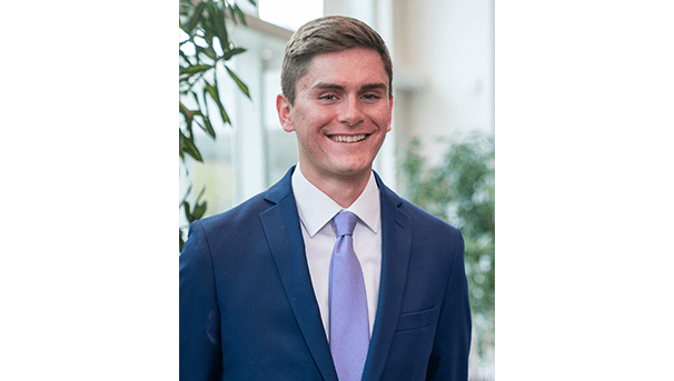 Jackson Stoller's professional headshot. He wears a blue blazer and a light purple tie