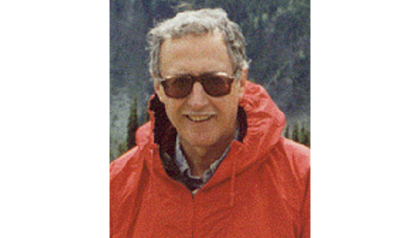 Picture of Dr. Charles Corbato. He stands with a large mountain side behind him