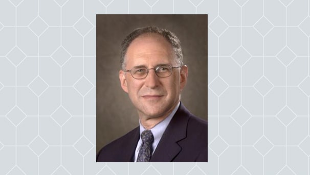 Robert Holub's professional headshot. He is against a light grey, patterned background