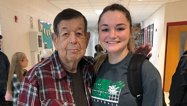 Harry Cleland and a teenage girl stand beside one another in a crowded hallway