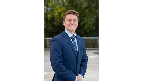 Blake Dodson's professional headshot. He wears a blue suit and multicolored tie