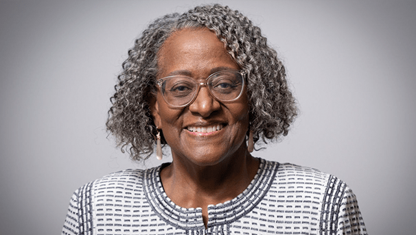 Dr. Powell smiling in front of a gray background