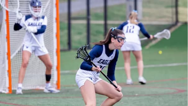 Three women's lacrosse athletes prepared to play defense.