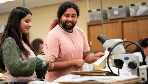 Two students in a lab class, female in the front, male in the back. They are conducting research