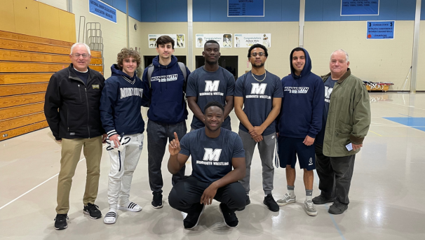 Group of wrestlers and coaches posing for a photo in Monmouth gear