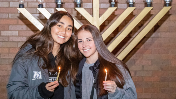Two female students at the menorah lighting ceremony on campus