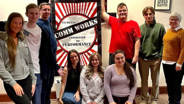 group of members holding up a sign with the commworks logo after a performance