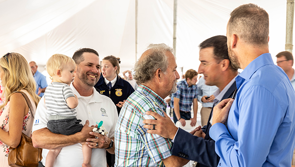 Group of individuals chatting at an outdoor event while shaking hands