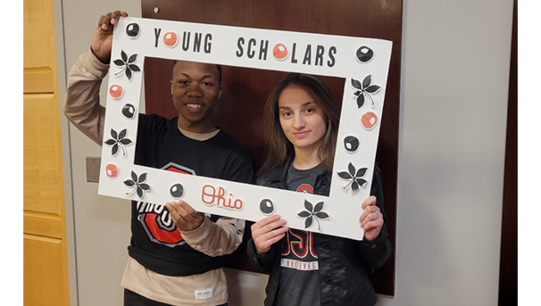 Two students smiling holding a Young Scholars Ohio frame around their face