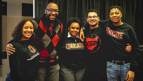 Five individuals standing next to each other smiling for a photo