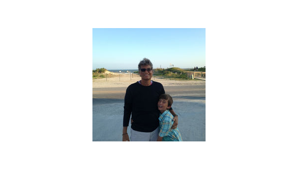 Two individuals standing next to each other smiling with the beach in the background