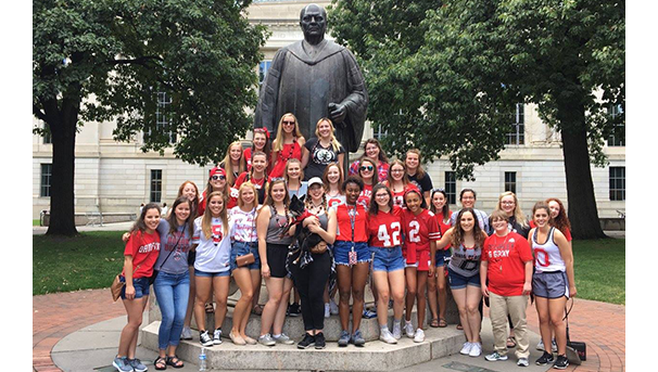 Members of the Women's Glee Club standing in front of the statue at the Thompson library