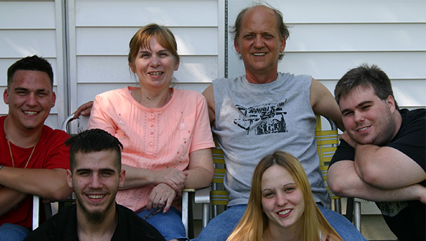 Six individuals sitting outside smiling for a group photo