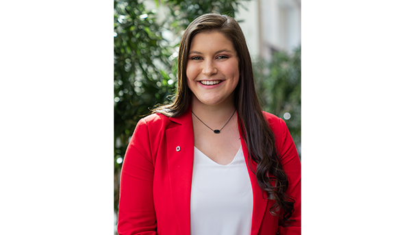 Maddie Allman's professional headshot. She wears a red blazer and a white undershirt