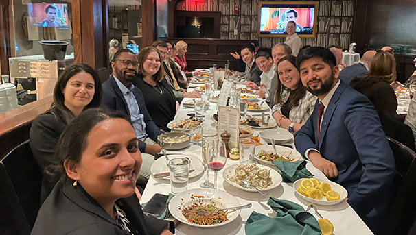 Group of individuals sitting at a table at a restaurant eating dinner